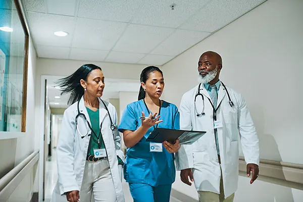 Two healthcare professionals walking and communicating in a hospital hallway