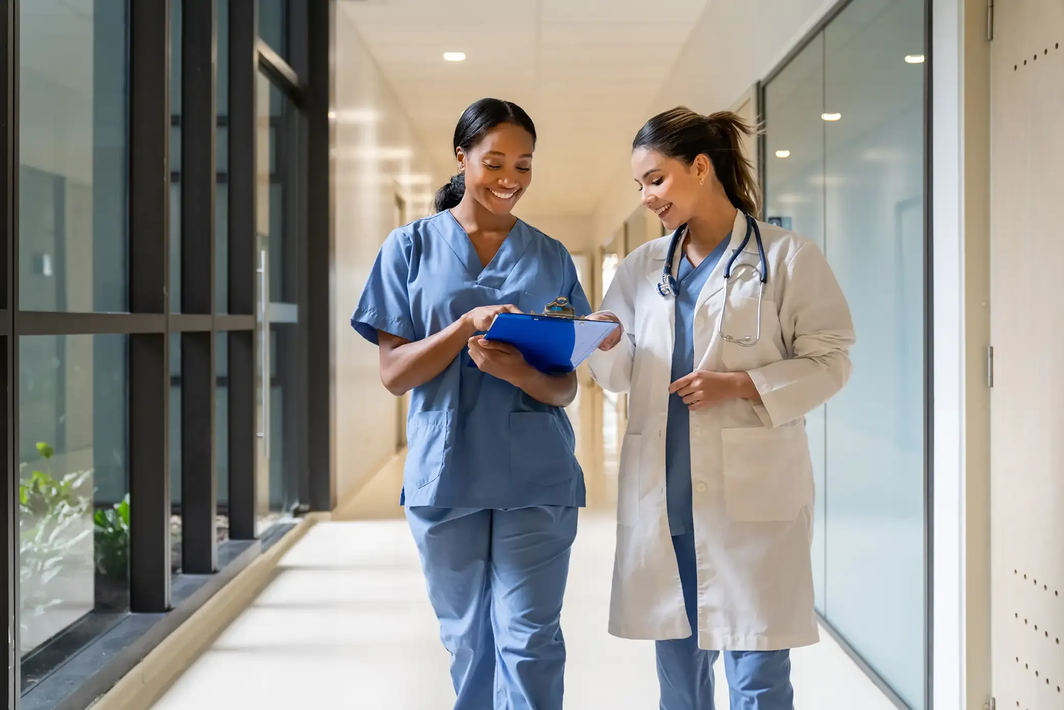 Two healthcare professionals walking and communicating in a hospital hallway